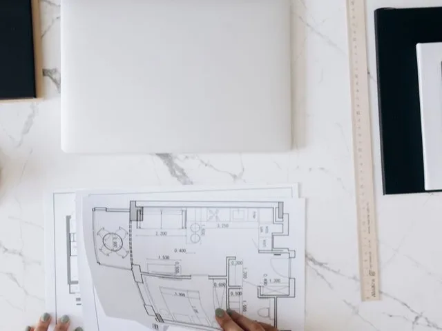 Műszaki terv és digitális alaprajz egyeztetése laptopon, tervezői asztalon